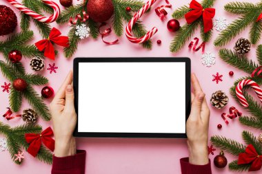 Evden Noel alışverişi, kadın elleri boş beyaz ekranlı tableti tutuyor. Kadın elinde tablet, boş ekran, Noel ağacı ve arka planda hediyeler..