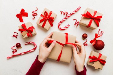 Kadınlar Noel tatili için sürpriz hediyeler hazırlıyor. İş yerinde el aletleri ve manzarayla oturuyor. Renkli masada Noel hediyesini paketleyen kadın..