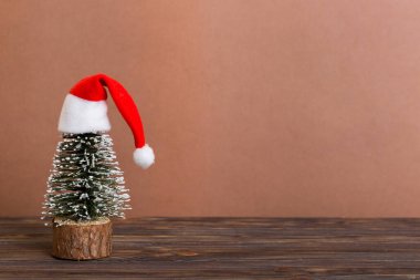 One small Christmas tree with santa hat on colored background. new year decoration with copy space.