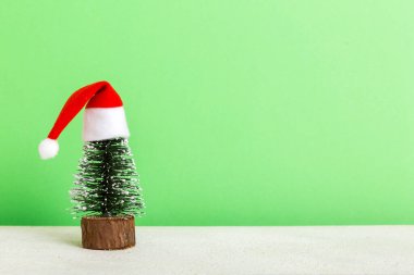 One small Christmas tree with santa hat on colored background. new year decoration with copy space.