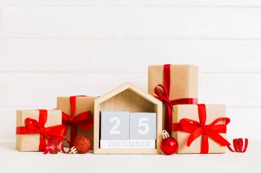 25 december. Christmas composition on colored background with a wooden calendar, with a gift box, toys, bauble copy space.