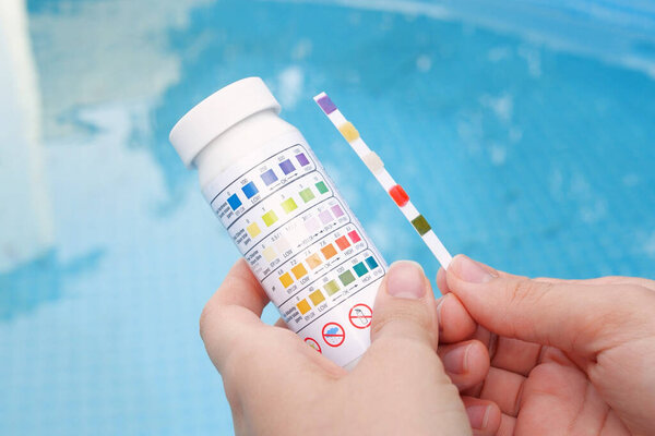 Анализ PH и хлора воды в бассейне летом. Проверка качества воды с тестовой полосой, сравнение результатов.