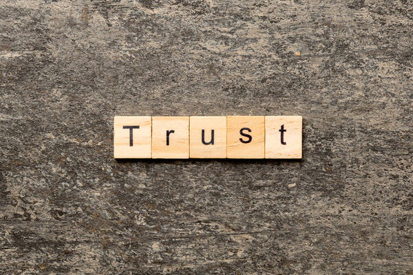 TRUST word written on wood block. TRUST text on table, concept.