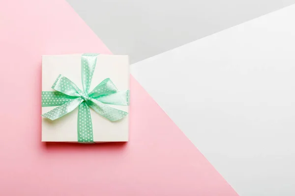 holiday handmade white present tied green ribbon bow top view with copy space. Flat lay holiday background. Birthday or christmas present. Christmas gift box concept with copy space.