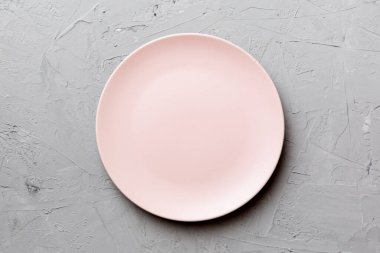 Çimento arka planındaki boş pembe tabağın üst görüntüsü. Tasarımın için boş boşluk.