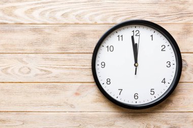 New year celebration concept with a bottle of champagne and two glasses toasting. Christmas gift box, alarm clock and fir tree branch on colored table. Top view Copy space.