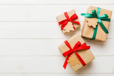 wrapped christmas or other holiday handmade present in paper with colored ribbon. Present box, decoration of gift on colourfull table, top view with copy space.