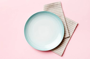 Renkli arkaplanda üst görünüm yiyecek için mavi tabak üzerinde boş. Tasarımınız için boşluk olan peçeteye boş tabak.