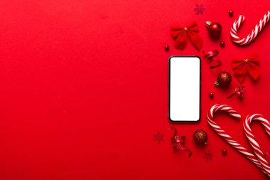 Mesaj atmak için yeri olan bir Noel modeli. Noel reklamı, uygulama şablonu. Masa arkasında boş ekran olan el ele tutuşan telefon. Mutlu yıllar ve Xmas Flat.