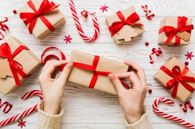 Kadınlar Noel tatili için sürpriz hediyeler hazırlıyor. İş yerinde el aletleri ve manzarayla oturuyor. Renkli masada Noel hediyesini paketleyen kadın..