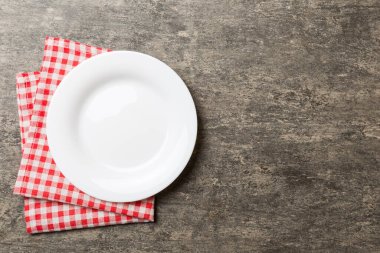 Renkli arka planda üst görünüm yiyecek için masa örtüsü üzerindeki boş yuvarlak beyaz tabak. Tasarımınız için boşluk olan peçeteye boş tabak.