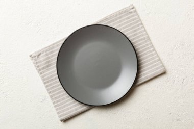 Renkli arka planda üst görünüm yiyecek için masa örtüsü üzerindeki boş yuvarlak gri tabak. Tasarımınız için boşluk olan peçeteye boş tabak.