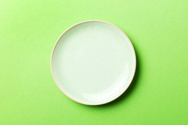 Renkli arka plan görüntüsünün üst görüntüsü yiyecek için boş, yuvarlak bej bir tabak. Tasarımınız için alanı olan boş tabak.