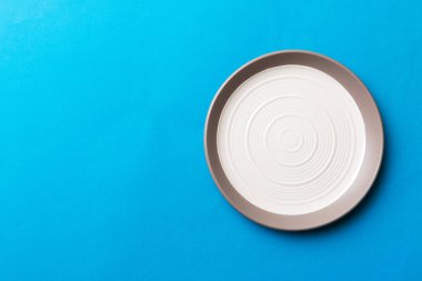 Renkli arka plan görüntüsünün üst görüntüsü yiyecek için boş yuvarlak beyaz tabak. Tasarımınız için alanı olan boş tabak.