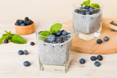 Sağlıklı kahvaltı ve chia tohumlu vanilyalı puding ve böğürtlenli masa arkası, vejetaryen gıda, diyet ve sağlık konsepti. Hindistan cevizi sütü ve yabanmersinli Chia pudingi..