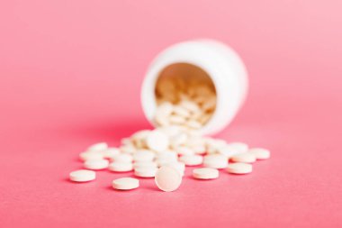 Medicine bottle and white pills spilled on a light background. Medicines and prescription pills flat lay background. White medical pills and tablets spilling out of a drug bottle.