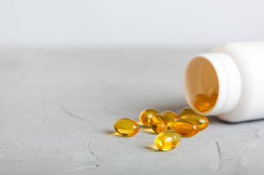 Yumuşak jel hapları ve Omega-3 yağı hap şişesinden sızıyor. Jel kapsülleri beyaz yüzey şişesi. Omega 3, multivitamin, kalsiyum, antibiyotik. Sağlığa. Dokunulmazlık.