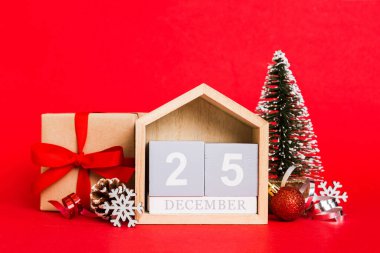 25 december. Christmas composition on colored background with a wooden calendar, with a gift box, toys, bauble copy space.