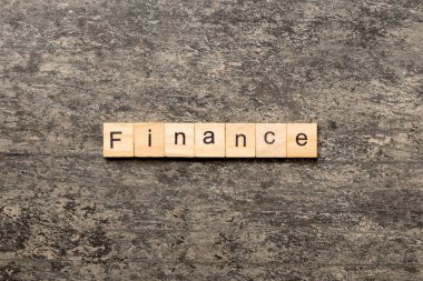 Tahta bloğa yazılmış finans sözcüğü. Deksing, konsept için çimento üzerinde FINANCE metin.