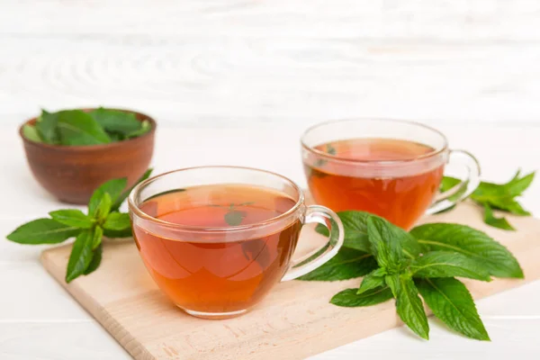 Cup of mint tea on table background. Green tea with fresh mint top view with copy space.