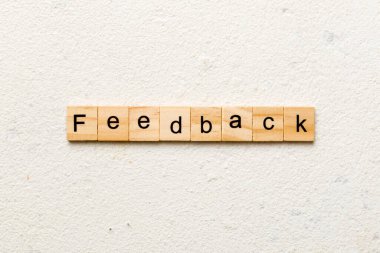 Tahta blokta yazan geri bildirim kelimesi. Deksing, konsept için çimento masadaki geri bildirim metni.