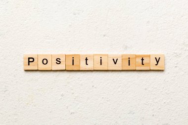 Tahta bloğa olumlu bir kelime yazılmış. Çimento sehpası üzerinde pozitif metin desing, konsept için.