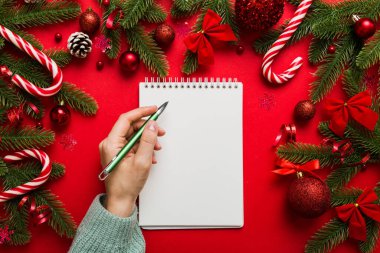 Noel 'i yazmak için bir kadın not defterine Xmas dekorasyonlu renkli arkaplan çiziyor.