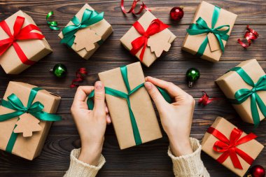 Kadınlar Noel tatili için sürpriz hediyeler hazırlıyor. İş yerinde el aletleri ve manzarayla oturuyor. Renkli masada Noel hediyesini paketleyen kadın..