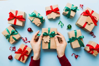 Kadınlar Noel tatili için sürpriz hediyeler hazırlıyor. İş yerinde el aletleri ve manzarayla oturuyor. Renkli masada Noel hediyesini paketleyen kadın..