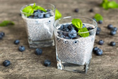 Sağlıklı kahvaltı ve chia tohumlu vanilyalı puding ve böğürtlenli masa arkası, vejetaryen gıda, diyet ve sağlık konsepti. Hindistan cevizi sütü ve yabanmersinli Chia pudingi..