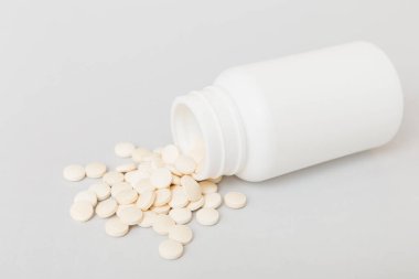 İlaç şişesinden alınan farklı uyuşturucu ve sağlık takviyesi hapları ve renkli arka plana ilişkin tıbbi genel görünüm.