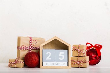 25 december. Christmas composition on colored background with a wooden calendar, with a gift box, toys, bauble copy space.
