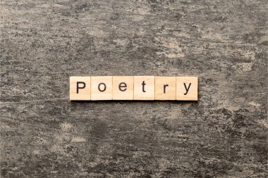 Tahta blokta yazılmış bir şiir kelimesi. Üst görünüm konseptiniz için çimento masadaki şiir metni.