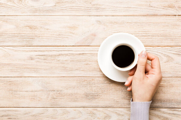 Minimalistic style woman hand holding a cup of coffee on Colored background. Flat lay, top view espresso cup. Empty place for text, copy space. Coffee addiction. Top view, flat lay.