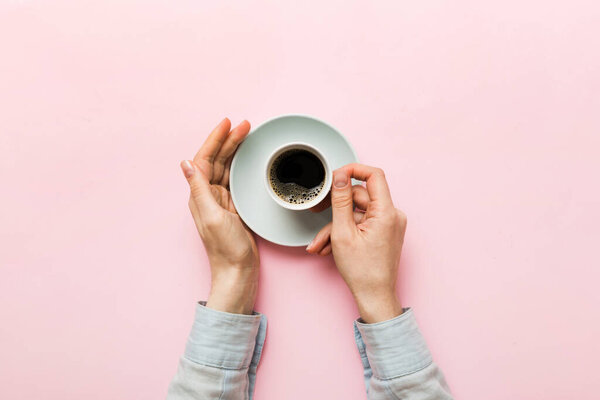 Minimalistic style woman hand holding a cup of coffee on Colored background. Flat lay, top view espresso cup. Empty place for text, copy space. Coffee addiction. Top view, flat lay.