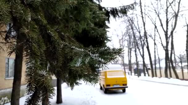 冬の雪の日を背景に スプルースの枝と黄色のぼやけた車で冬の風景 — ストック動画