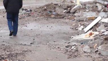 Şehirdeki bombalamadan sonraki kalıntılar. Şehre yapılan hava saldırısından sonra harabelerin arkasında yürüyen bir adamın arkadan görünüşü..