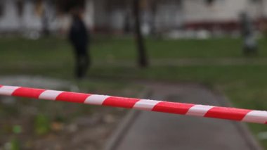 Kırmızı-beyaz bariyer bandının arka planında yürüyen insanların siluetleri. Kırmızı ve beyaz bariyer bandı yayalar ve insanlar için tehlikeli bir yer olduğunu gösteriyor..