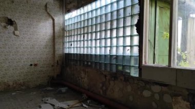 Terk edilmiş eski bir binanın içinde. Binanın içinde kırık camları ve eski püskü duvarları olan bir oda. Eski cam duvarlar..