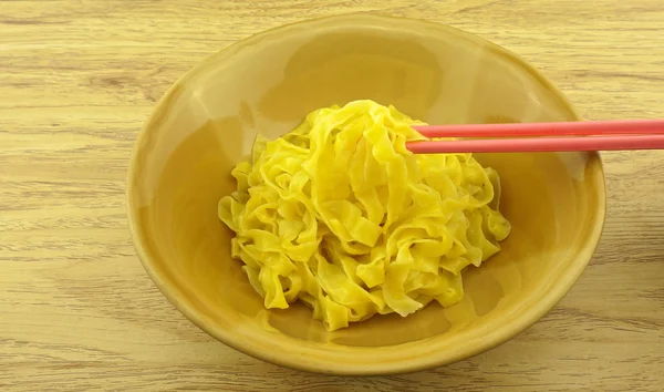 Comer fideos grandes de color amarillo escaldado en un tazón marrón —  Fotos de Stock