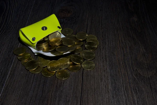 Light green pocket has gold coin gush on wood — Stock Photo, Image