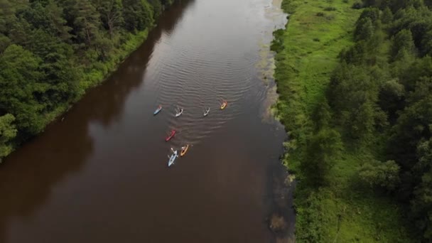 Воздушный полет над группой каяков, плывущих вдоль реки в клине — стоковое видео