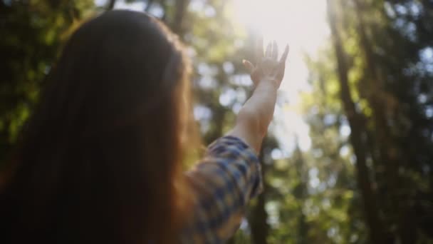 Красива дівчина тягне руку до сонця, граючи з променями — стокове відео
