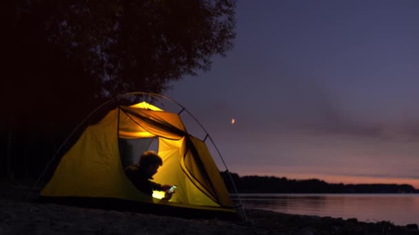 旅行者躺在帐篷里用智能手机看新闻 — 图库视频影像