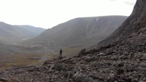 Légi kilátás egy széles völgy és egy turista figyeli a hegyeket a szikláról — Stock videók