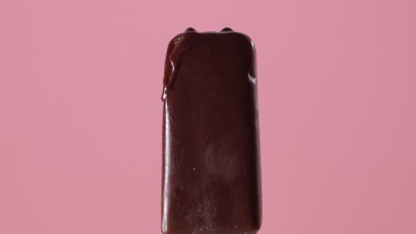 Círculos temporais. Sorvete de chocolate derrete rapidamente em um fundo rosa — Vídeo de Stock
