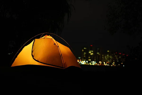 A young guy in jacket sitting inside of orange tent and looking at smartphone — Stock Photo, Image