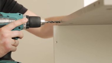 Genç bir adam ahşap bir masa deliyor.