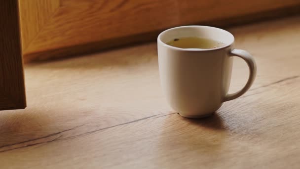 Café recién hecho por la mañana en una taza de café espresso blanco en un alféizar de madera — Vídeos de Stock