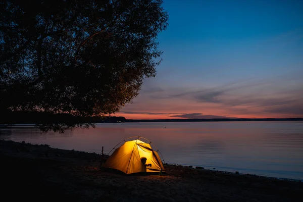 旅行者は輝くテントの近くのキャンプチェアに座っています — ストック写真